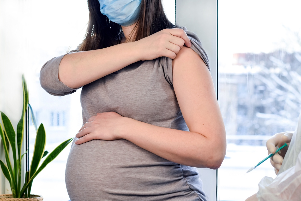 Pregnant Vaccination. Pregnant Woman In Face Mask Getting Vaccinated in Clinic. Doctor Giving Corona Virus Vaccine Injection Patient. Covid-19 Flu Protection.