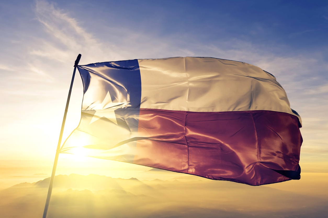 Texas flag on flagpole textile cloth fabric waving on the top with sunse